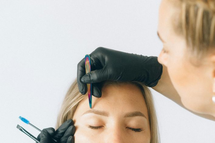 Professional eyebrow shaping and microblading session captured indoors.