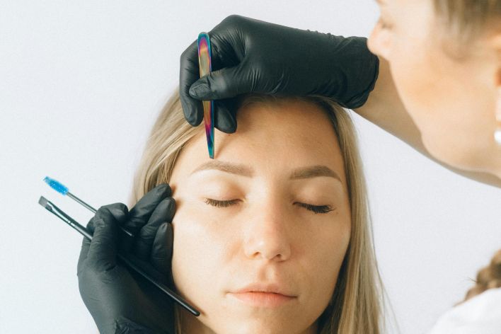 Professional eyebrow shaping and microblading session captured indoors.