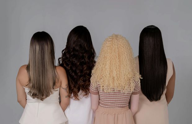 Four women showing diverse hairstyles from behind, emphasizing hair texture and color.